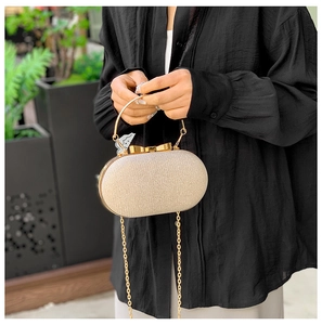 Borsa da sera color champagne con chiusura a fiocco e glitter tenuta da una modella