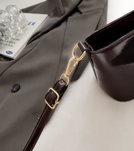 Detail der dunkelbraunen, glänzenden Handtasche mit goldfarbenen Metallbeschlägen