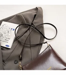 Detail der dunkelbraunen Leder-Eimertasche mit goldenem Logo und verstellbarem Gurt