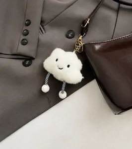 Nahaufnahme eines weißen flauschigen Wolkenanhängers mit lächelndem Gesicht an Handtasche