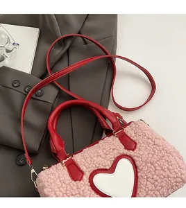 Detail view of pink plush cylinder bag with heart applique and red leather handles