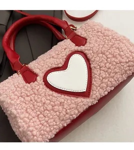Detail of pink faux fur barrel bag featuring a white leather heart and red handles