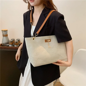 Beige canvas tote bag with brown leather straps and deer charm on a female model