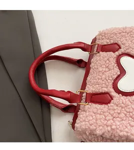Close-up of pink faux shearling cylinder bag with red leather handles and gold metal buckles