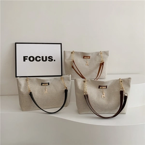 Three minimalist canvas tote bags with metal chain straps and deer charms on white pedestals