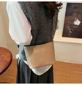Dettaglio di una borsa a secchiello in pelle marrone chiaro indossata da una modella