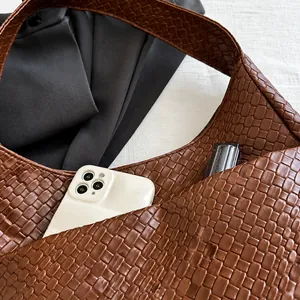 Detalle de bolso hobo de piel sintética trenzada marrón con interior espacioso para objetos