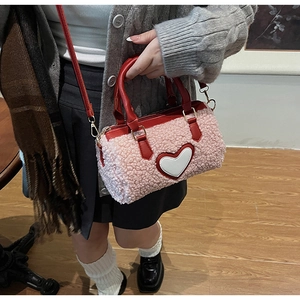 Détail du sac cylindrique en peluche rose avec bandoulière cuir rouge et coeur