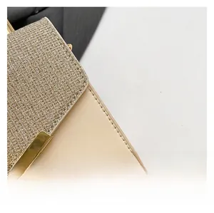 Close-up of the beige leather handbag featuring sparkling golden fabric and stitching