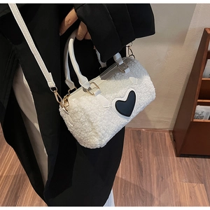 Detail of white lambskin cylindrical bag with black heart patch and golden hardware