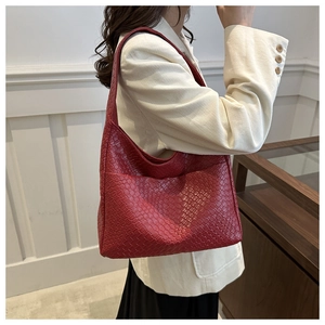 Close-up of red woven leather tote bag shown on model with striped blazer jacket