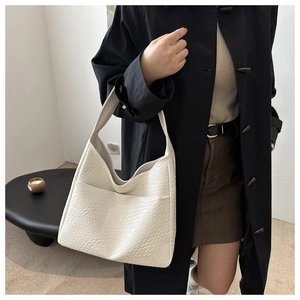Detail of off-white woven texture tote bag with a functional front pocket and wide strap