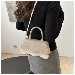 Detail of elegant beige and glitter gold crossbody bag with wavy edge and metal handle