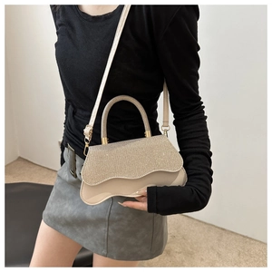 Detail of glitter flap and wavy base on a chic beige crossbody bag with top handle