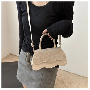 Detail of trendy crossbody bag with glitter texture and wave-shaped bottom edge