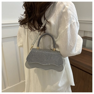 Detailed view of silver rhinestone crossbody bag with wavy edge design and gold hardware