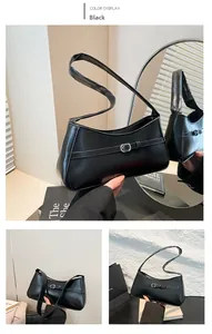 Detail of black faux leather baguette bag featuring a silver buckle and matte finish