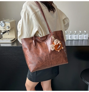 Détails du sac cabas vintage en cuir marron avec un pendentif aile en peluche