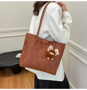 Détail de la texture d'un sac cabas vintage en cuir marron avec breloque peluche
