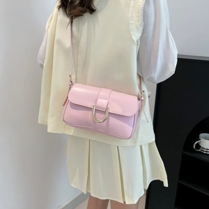 Pink minimalist crossbody bag with gold hardware shown on model in white outfit