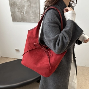 Red suede tote bag with bow detail worn by model on shoulder for autumn style