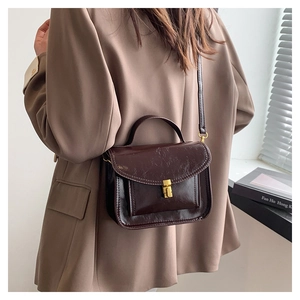 Sac messager vintage en cuir huilé marron foncé porté par un mannequin en intérieur sobre