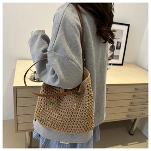 Detail of woven cotton tote bag with brown leather straps shown on a model's shoulder