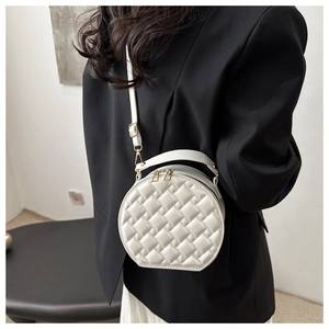 Detail of white puffy quilted crossbody bag with golden zipper on a black blazer