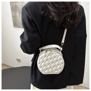 Detailed shot of white circular crossbody bag with woven texture and gold zipper chain