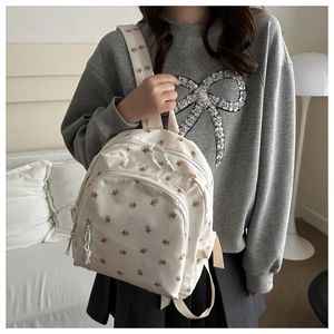 Detail of white floral backpack featuring premium nylon fabric and a triple compartment design