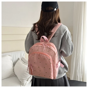 Detailed back view of a pink floral mini backpack worn by a model in a cozy room