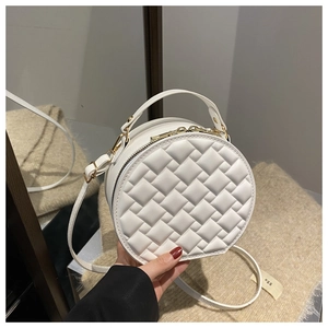 Detail of white round crossbody bag featuring quilted rhombus pattern and gold hardware