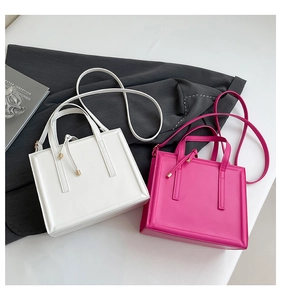 Close-up of rectangular leather shoulder bags with gold hardware in cream and rose red