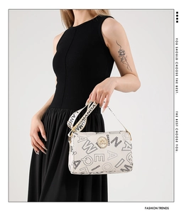 Detailed shot of white PU leather cylinder bag featuring wide logo strap and gold logo