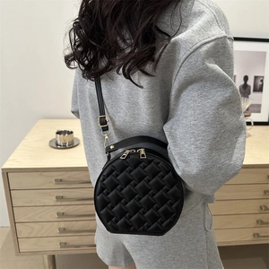 Chic black round quilted crossbody bag with golden chain and sleek minimalist design