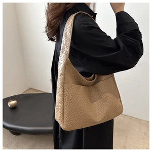 Close-up of stylish light brown tote bag with crocodile pattern worn on shoulder