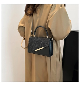 Detail of a chic black PU leather bag with glitter texture and gold metal accents