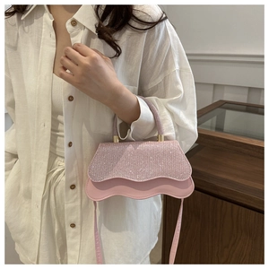 Detail of pink wavy-edge handbag featuring sparkling sequins and gold metal handle