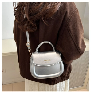 Silberne Satteltasche als Umhängetasche an einem Model mit feinem Riemendetail gezeigt