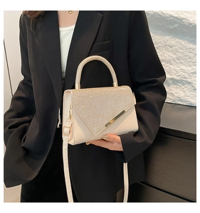 Detail of a beige PU leather bag with V-shaped rhinestone flap and sparkling top handle