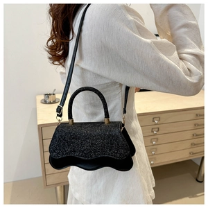 Detail of black glitter crossbody bag featuring unique wavy edge design and slim strap