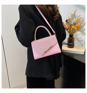 Pink sequin flap handbag with gold metal trim and leather strap on a black blazer