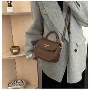 Nahaufnahme einer braunen Vintage-Lederhandtasche mit goldener Logo-Prägung am Modell