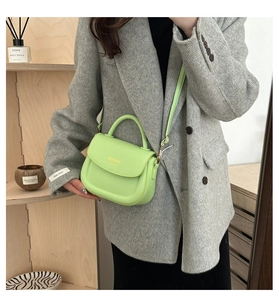 Mintgrüne Satteltasche mit goldenem Schriftzug auf grauem Blazer-Outfit getragen
