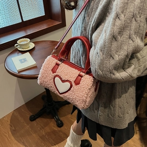 Sac à main cylindrique en peluche rose avec écusson cœur blanc et bandoulière rouge