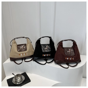 Detailed view of khaki, black, and brown canvas tote bags with leather bottom and dog logo