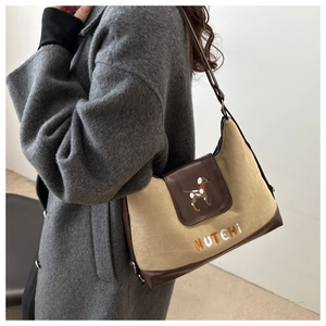 Close-up of canvas underarm bag featuring puppy embroidery and brown leather trim
