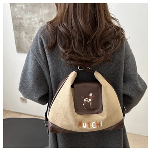 Detail of canvas tote featuring dog embroidery and MUTEHI lettering on brown leather flap