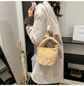 Detail van beige pluche bucket bag met zachte lamswol textuur en CLEAR-letterpatch erop