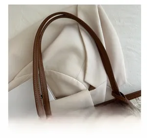 Detailed close-up of brown leather handles and vintage monogram pattern on tote bag